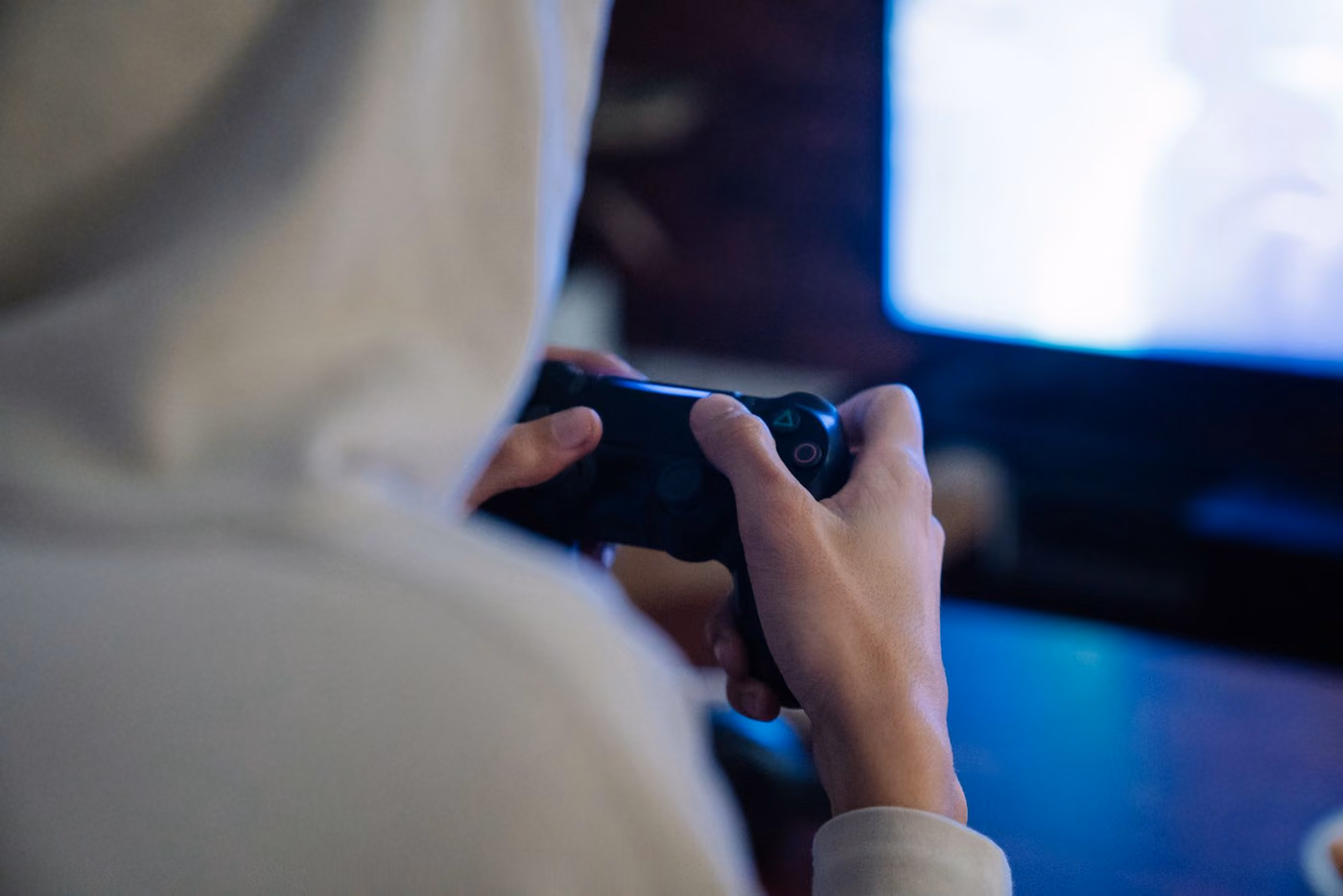 Pessoa segurando controle de videogame, focada na tela em frente