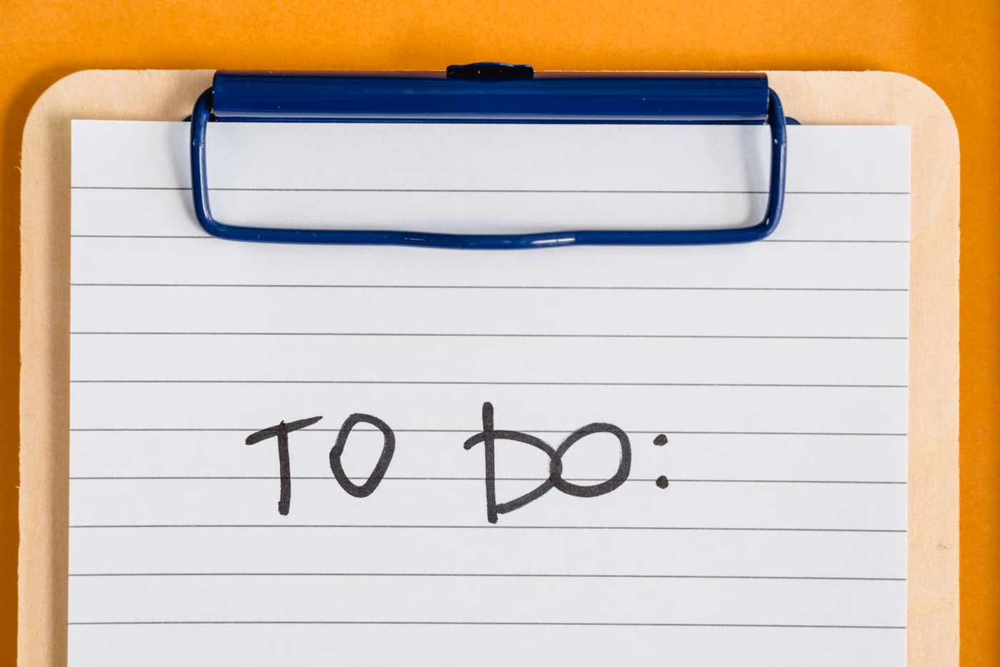 Prancheta com folha de papel escrito "to do" em letra manuscrita